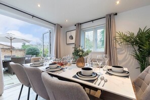 Un comedor con una mesa dispuesta para cuatro personas, rodeada de sillas, y vistas al exterior.
