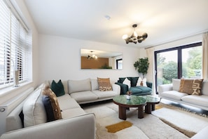 A modern living room with a sectional sofa, a coffee table, and a large window with curtains.