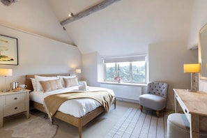A bedroom with a bed, bedside table, chair, desk, and window. - Cotswold Hillside Retreat with Stunning Views (Stroud)