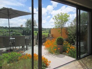 A patio area with outdoor furniture and a view of a garden with orange flowers.