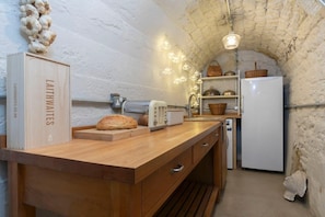 A rustic kitchen with a wooden countertop, a white refrigerator, and a hanging light fixture. - Cotswold Hillside Retreat with Stunning Views (Stroud)