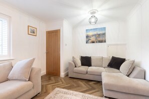 A living room with a beige sofa, a wooden door, and a painting on the wall. - Peaceful 3-Bed Home in Tivoli (Gloucestershire)