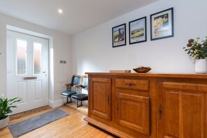 A kitchen with a wooden cabinet, a white door, and three framed pictures on the wall. - Charming Two Bedroom Apartment in Fairview (Gloucestershire)