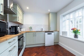 A modern kitchen with light-colored cabinets, a dishwasher, and a window with a view. - Charming Two Bedroom Apartment in Fairview (Gloucestershire)