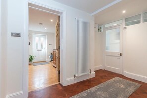 A hallway with a radiator, a door, and a rug. - Charming Two Bedroom Apartment in Fairview (Gloucestershire)