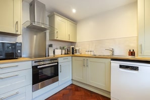 A modern kitchen with stainless steel appliances, light-colored cabinets, and a wooden countertop. - Charming Two Bedroom Apartment in Fairview (Gloucestershire)