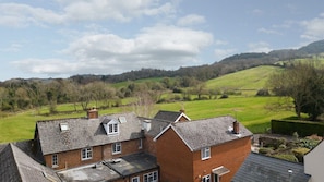 A residential area with houses, a green field, and hills in the background.