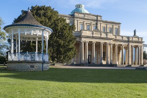 Ein großes Gebäude mit Kuppel und Säulen, einem Pavillon und einem gepflegten Rasen.