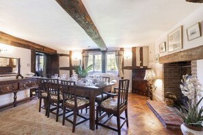 A dining area with a wooden table set for six, surrounded by chairs with patterned cushions.