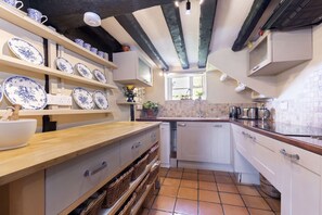 A kitchen with white cabinets, a wooden countertop, and blue and white patterned plates on shelves.