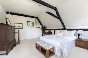 A bedroom with a bed, a wooden bench, a dresser, and a nightstand. - Beautiful 4 Bedroom Cotswold Thatched Cottage (Twigworth)