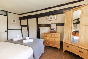 Een slaapkamer met een groot bed, een houten dressoir en een spiegelkast.