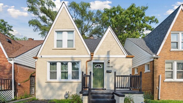 A two-story house with a green door, a number 16646, and a front yard with a small garden and steps leading to the entrance. - Urban Delight  (Detroit)