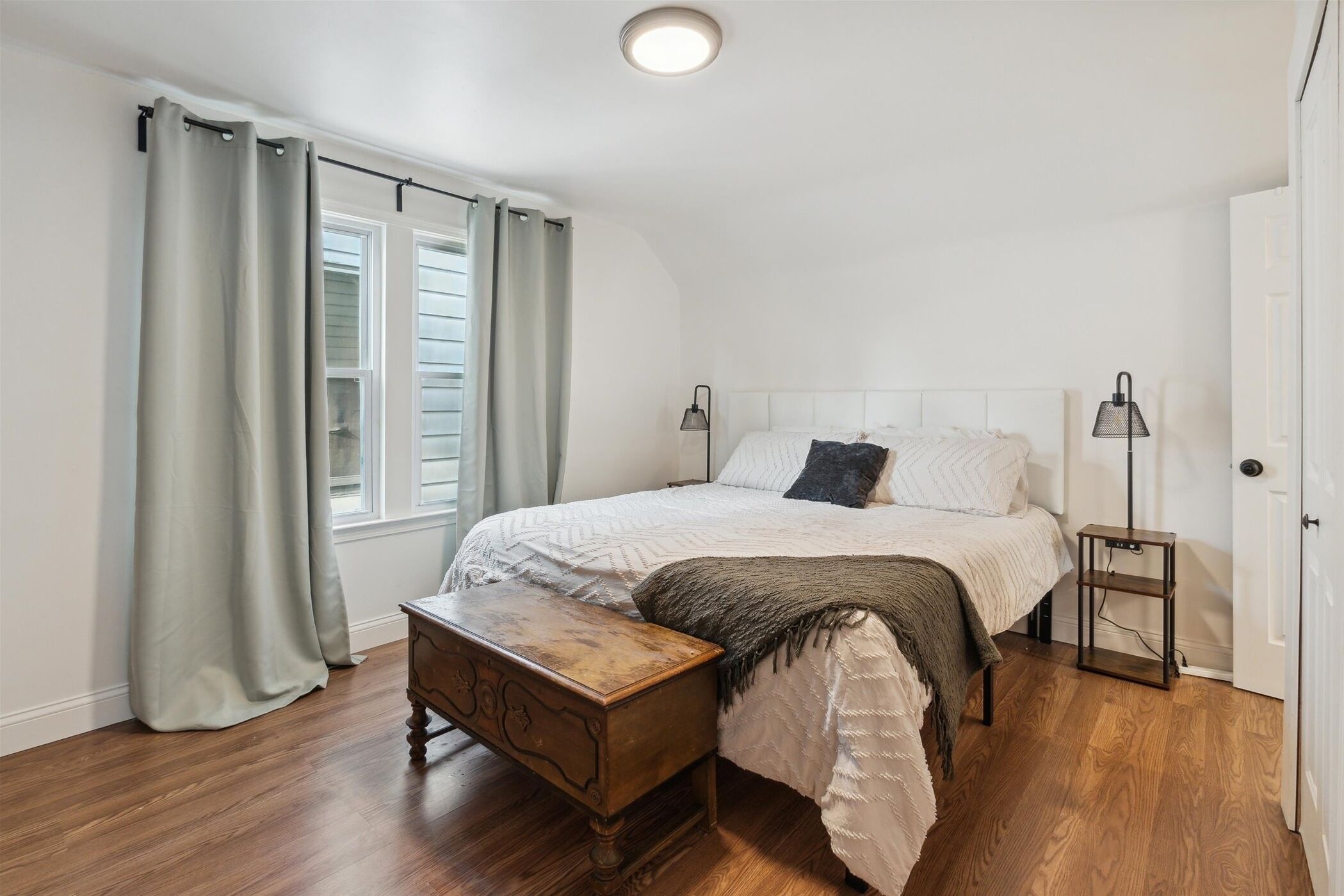 Une chambre à coucher avec un lit, une table de chevet en bois et une petite table.