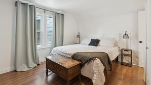 A bedroom with a bed, wooden nightstand, and a small table. - Urban Delight  (Detroit)