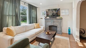 A living room with a sofa, coffee table, fireplace, and a painting on the wall. - Urban Delight  (Detroit)