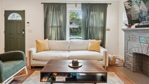 A living room with a sofa, a coffee table, a fireplace, and a television. - Urban Delight  (Detroit)