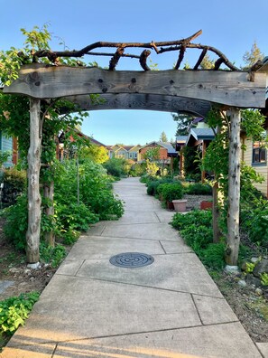 A wooden arbor over a concrete pathway leading to a residential area with houses in the background. - cozy townhouse in a chill Portland co-housing community - sauna, hot tub (Portland)