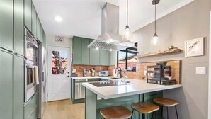 A modern kitchen with a central island, bar stools, stainless steel appliances, and pendant lighting. - Sedona Stargazer Retreat w/ Spa! (Sedona)