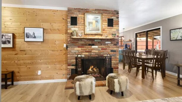 A cozy living room with a brick fireplace, wooden walls, and a dining area with a table and chairs. - Sedona Stargazer Retreat w/ Spa! (Sedona)