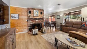 A living room with a fireplace, wooden walls, a dining area, and a sofa. - Sedona Stargazer Retreat w/ Spa! (Sedona)