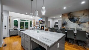A modern kitchen with a marble island, grey cabinetry, and pendant lighting. - Game Room, Hot Tub, Cold Plunge, Sauna, Fire Pit (Asheville)