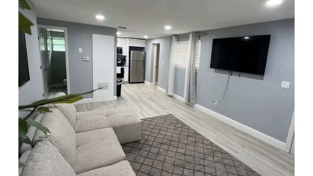 Een moderne woonkamer met een modulaire bank, een flatscreen televisie aan de wand en een kamerbreed tapijt met een patroon.