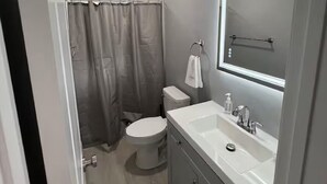 Een moderne badkamer met toilet, wastafel en douche.