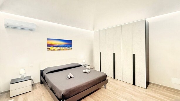 Een moderne slaapkamer met een bed, nachtkastjes, een kledingkast en een wandairconditioner.