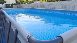 Une piscine rectangulaire dont l’intérieur est revêtu de carreaux bleus et dont le bord est blanc.