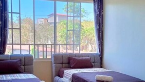 A room with two beds, a large window, and a view of the outside. - 2 bedroom family apartment in front of the beach on the malecon of san cristobal (Puerto Baquerizo Moreno, San Cristóbal)
