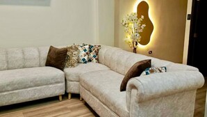A L-shaped sectional sofa with patterned cushions, a wall-mounted light fixture, and a wooden floor. - 2 bedroom family apartment in front of the beach on the malecon of san cristobal (Puerto Baquerizo Moreno, San Cristóbal)