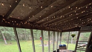 An outdoor patio with a barbecue grill, wooden table, and chairs.