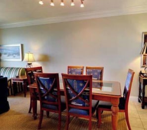 Un coin repas avec une table et des chaises, une lampe et un tableau au mur.