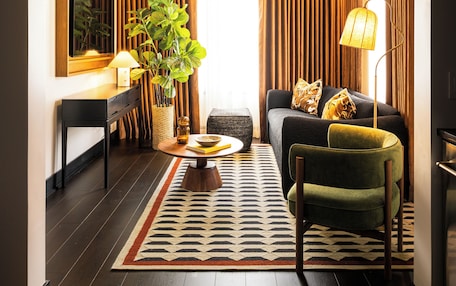 A modern living room with a sofa, armchair, coffee table, and a potted plant.