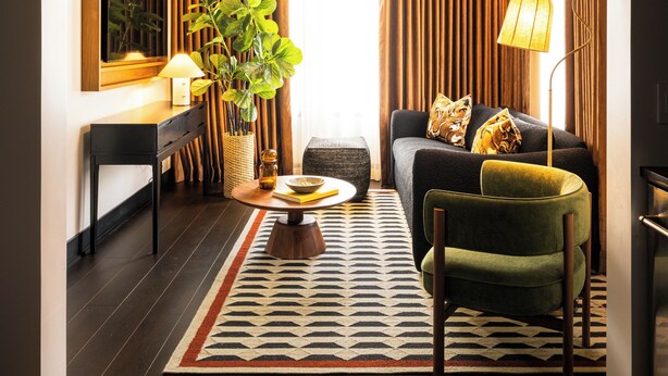 A modern living room with a sofa, armchair, coffee table, and a potted plant. - Hotel Albatross (Ocean Grove)