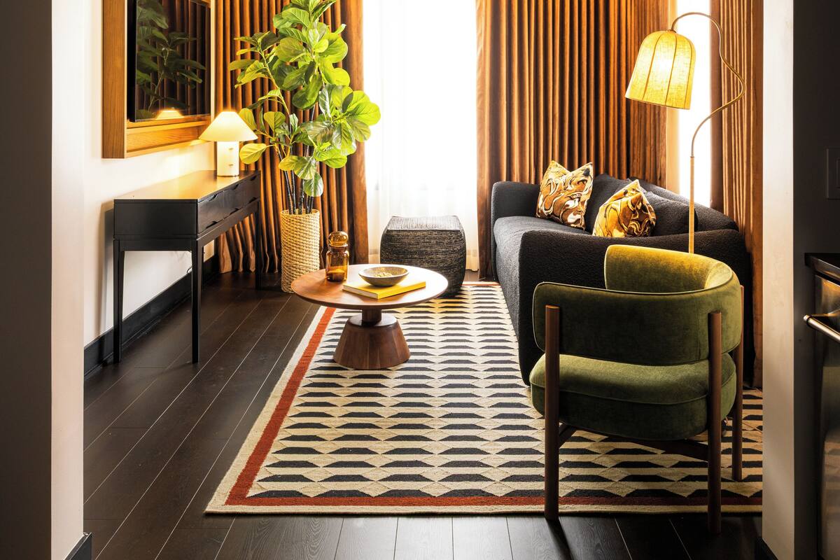 A modern living room with a sofa, armchair, coffee table, and a potted plant.