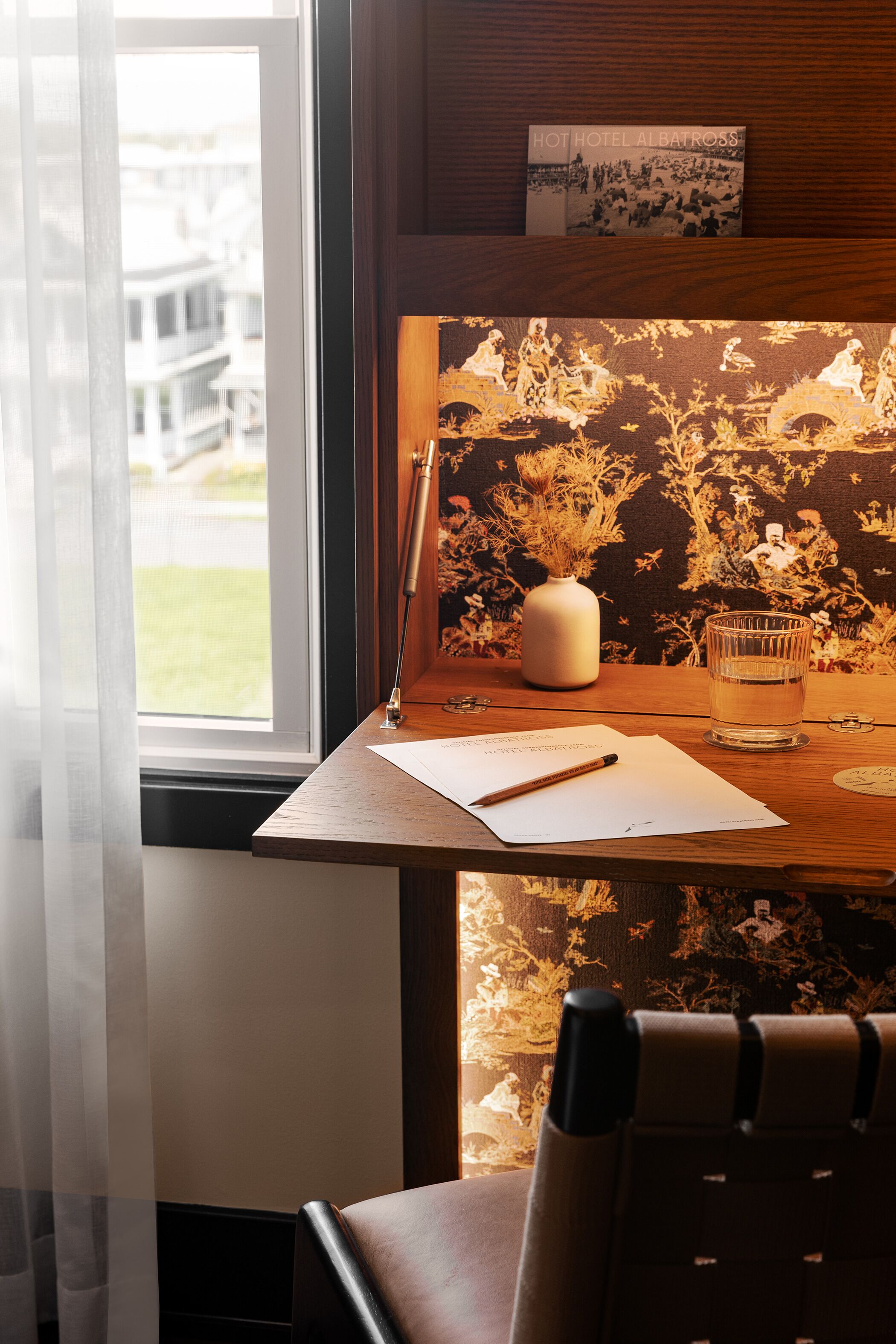 Un bureau en bois avec un vase, un verre d’eau et un stylo.
