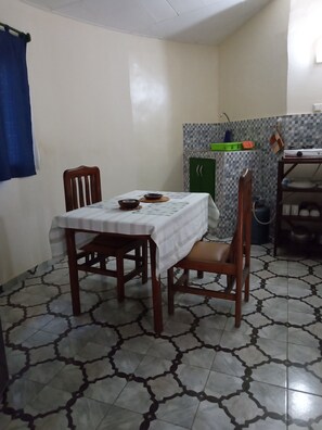 Una zona pranzo con tavolo apparecchiato per due, una cucina con schienale piastrellato e un pavimento decorato.