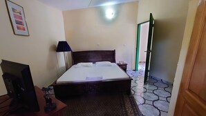 Une chambre à coucher bien rangée, avec un lit, un bureau, une lampe et un tableau encadré au mur.