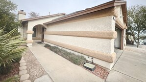 A single-story house with a stucco exterior, a covered patio, and a small garden area. - Cozy 2-bedroom house in Henderson with WiFi, AC, Solar (Henderson)
