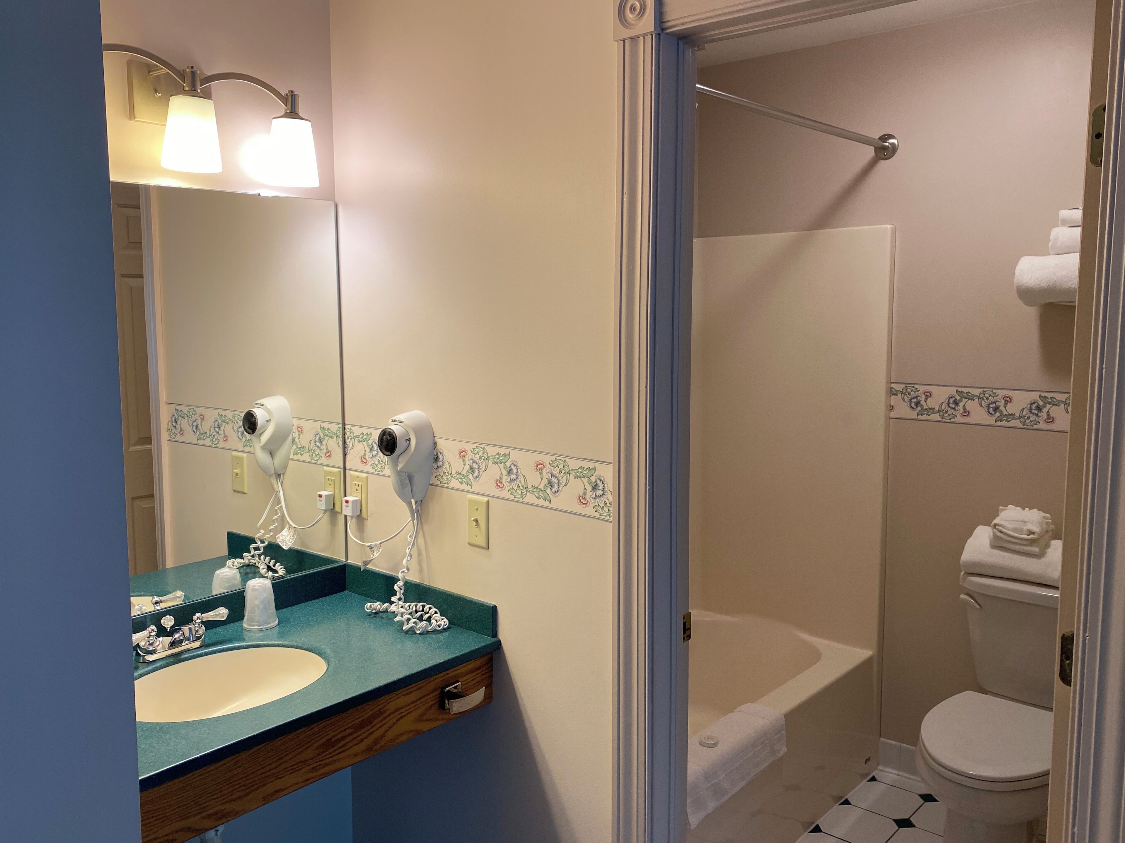 Une salle de bain équipée d’un lavabo, de deux sèche-cheveux, d’une douche et de toilettes.