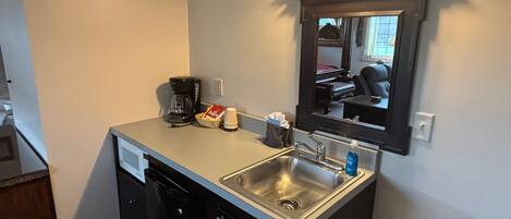 A compact kitchen with a built-in dishwasher, a coffee maker, and a sink.