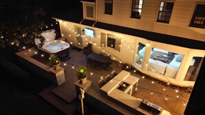 An outdoor patio with a hot tub, string lights, and seating areas.