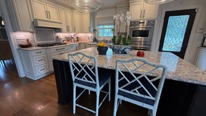 A modern kitchen with white cabinetry, granite countertops, and stainless steel appliances.