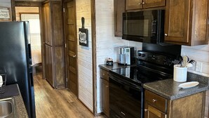 A kitchen with wooden cabinets, a black refrigerator, a microwave, a coffee maker, and a dishwasher.