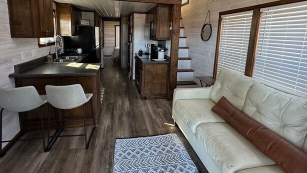 A compact, open-plan living space with a kitchenette, a dining area, and a seating area with a sofa and chairs.