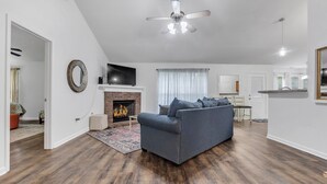 A modern living room with a grey sofa, a fireplace, and a ceiling fan. - Warm & Charming 4-BR in the Heart of Southaven-Near Stateline, Silo Square. (Southaven)