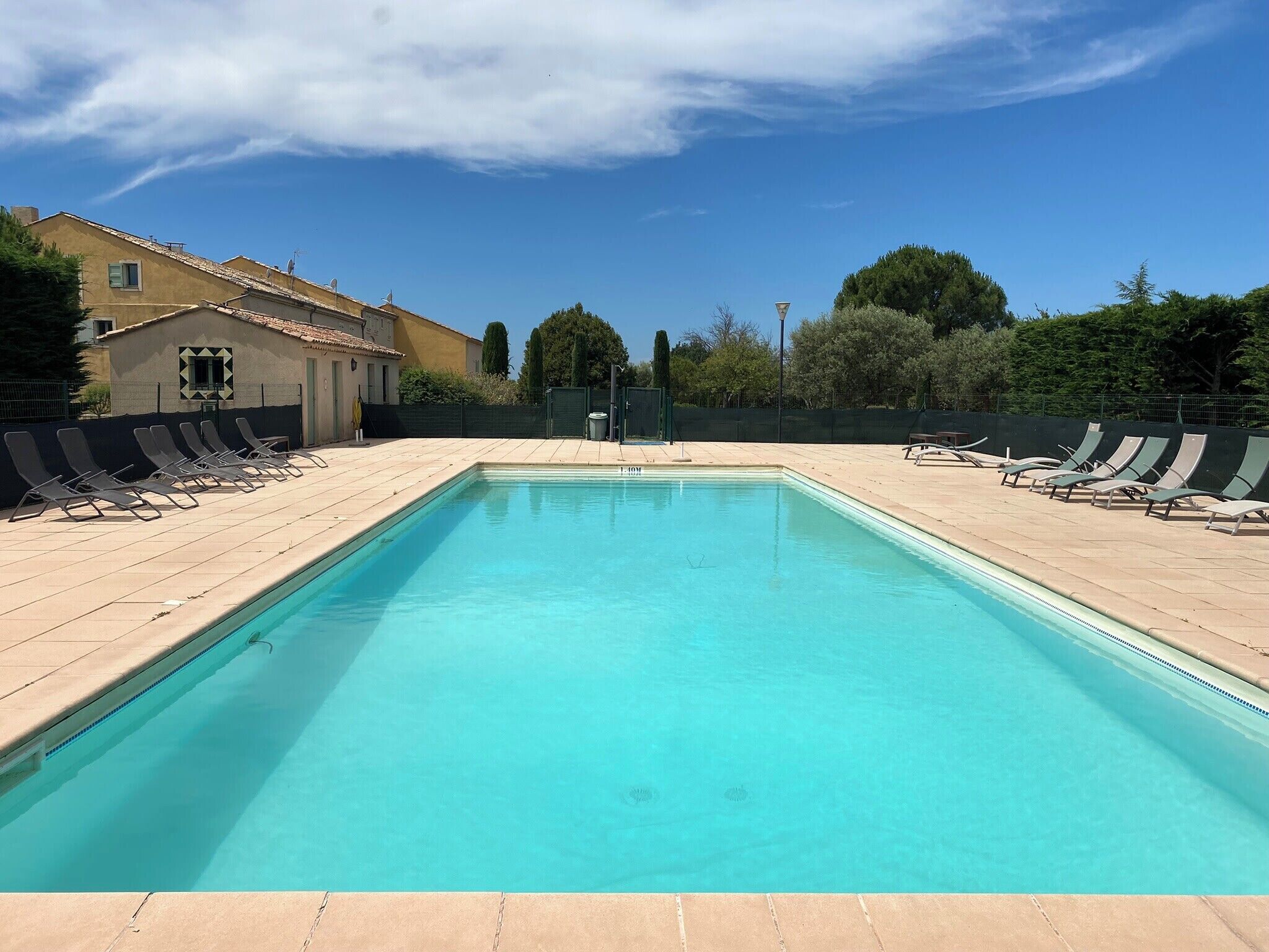 A rectangular swimming pool with clear blue water, surrounded by lounge chairs on both sides.