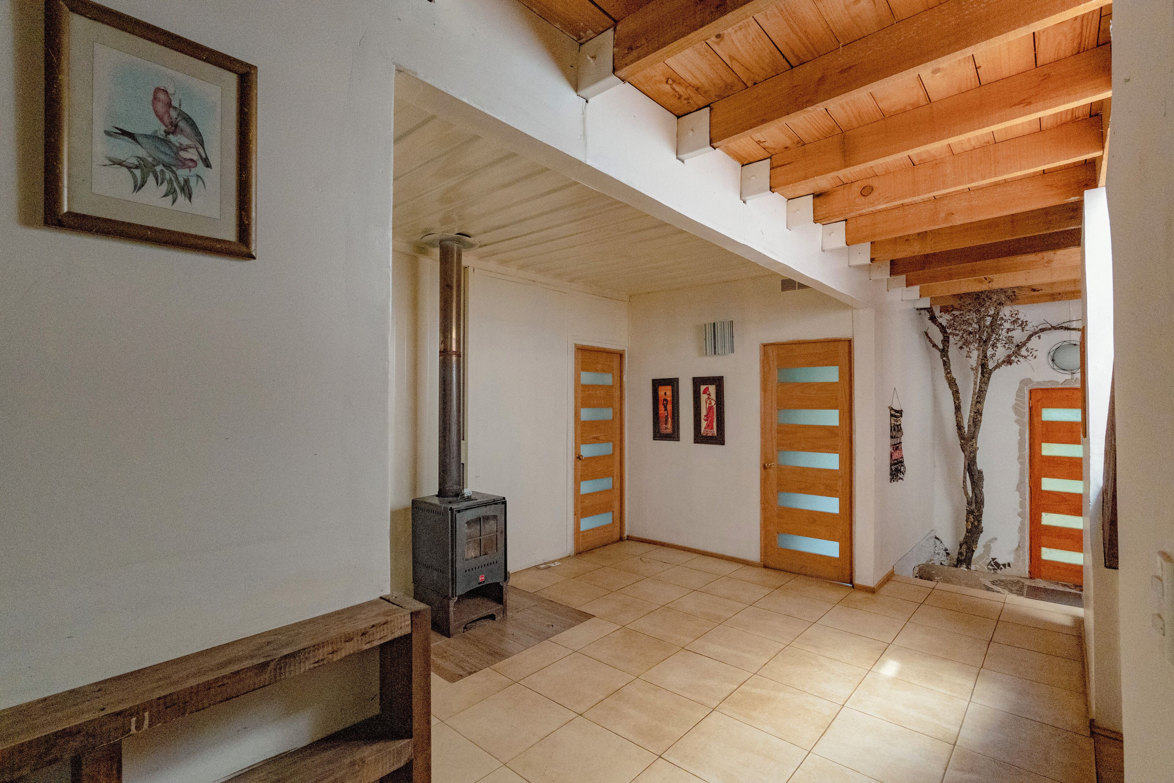 Un pasillo amplio con techo de madera, una estufa de leña y un cuadro enmarcado en la pared.